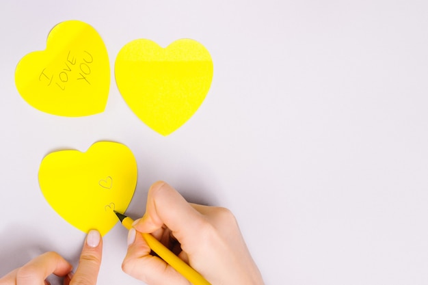 Mão escrever mensagem de amor em corações de nota iluminantes no fundo cinza final.