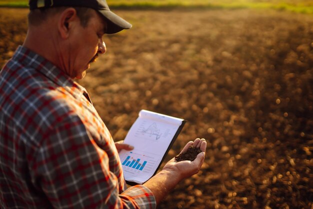 Foto mão especializada do agricultor verificando a saúde do solo antes do crescimento de uma semente de vegetais ou mudas de plantas