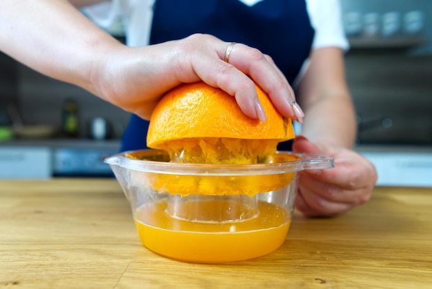 Mão espremendo suco de laranja fechar o processo de fabricação de bebidas frescas
