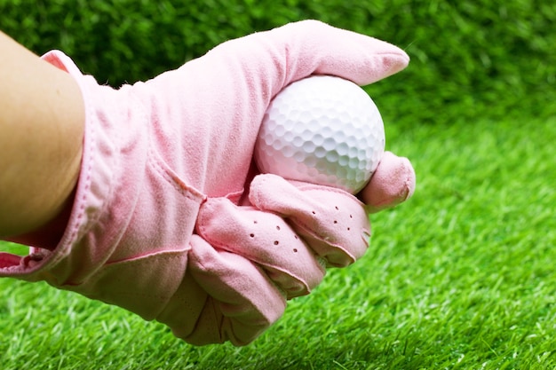 mão está segurando o golfe no fundo da grama verde