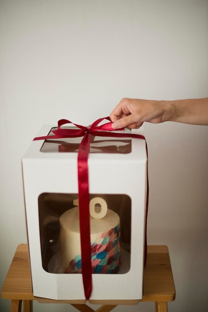 Mão feminina anônima abre uma caixa com um bolo para o 10º aniversário