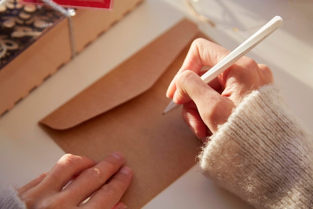 Mão feminina assina um envelope festivo Preparando-se para as férias de Natal