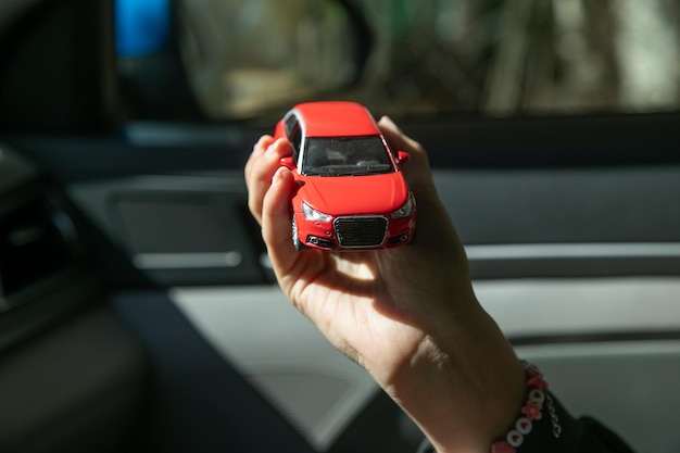 Mão feminina caucasiana mostrando carro de brinquedo vermelho