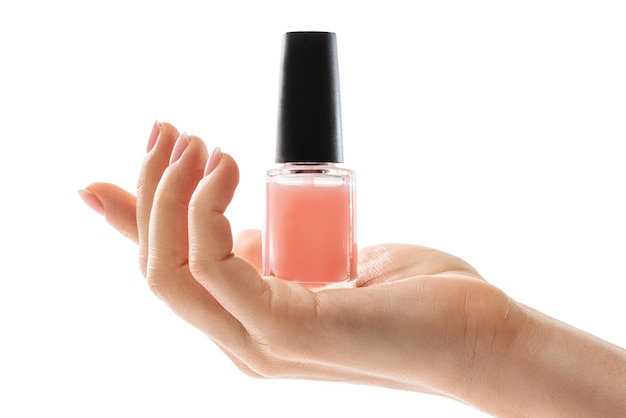 Mão feminina com bela manicure francesa segurando garrafa de esmalte rosa contra fundo branco