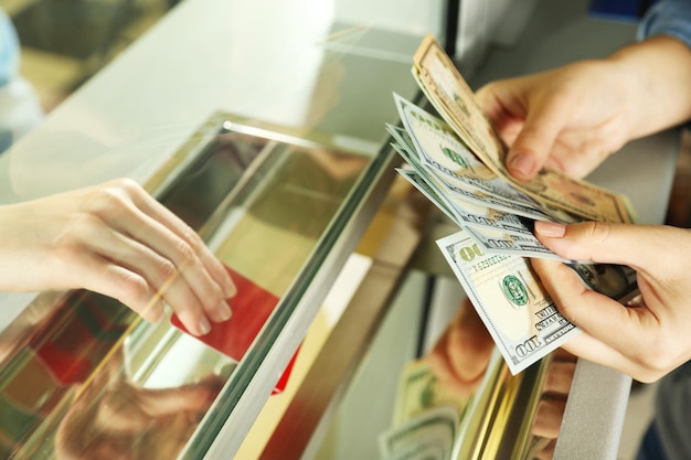 Mão feminina com dinheiro na janela do departamento de caixa Conceito de troca de moeda
