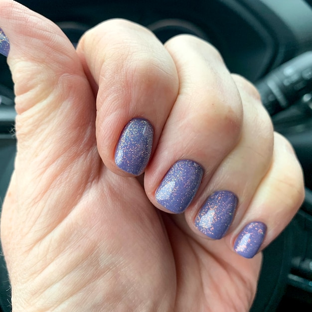 Mão feminina com esmalte brilhante no carro