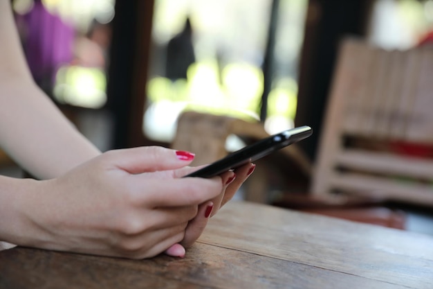 Mão feminina com estoque comercial de smartphone on-line em cafeteria ao ar livre, conceito de negócios