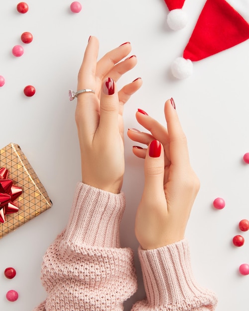 Mão feminina com manicure no fundo branco Natal dia dos namorados design de unhas brilhantes na moda