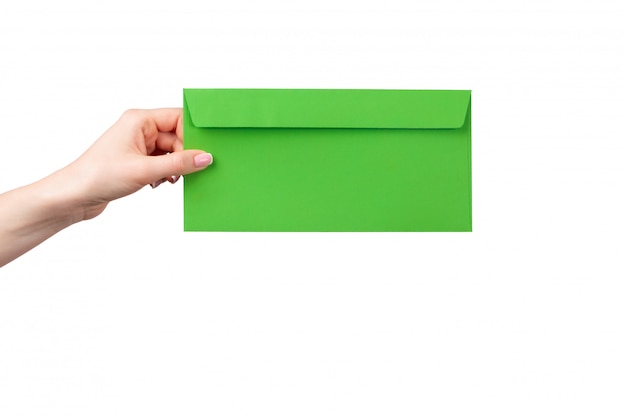 Mão feminina com manicure segurando o envelope verde