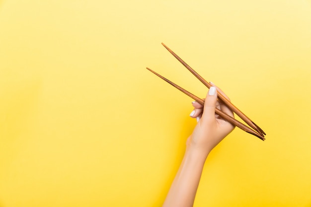 Mão feminina com pauzinhos. Comida asiática tradicional