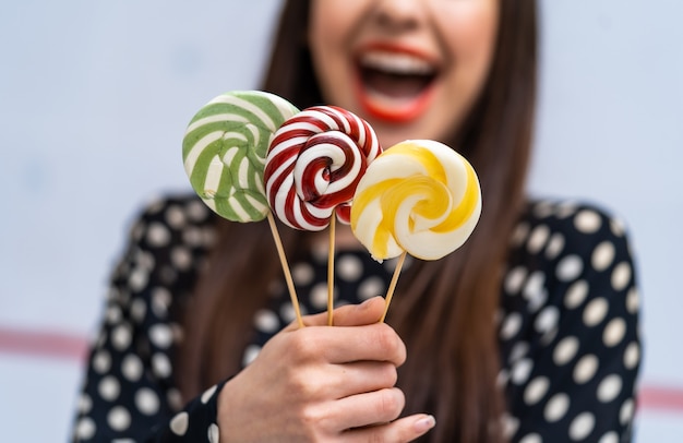 Mão feminina com pirulitos doces no fundo desfocado. Mão segurando pirulito isolado no fundo branco.