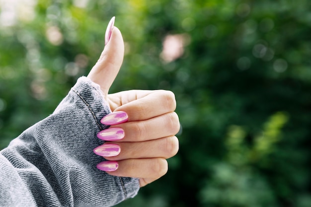 Mão feminina com uma bela manicure rosa mostra classe.