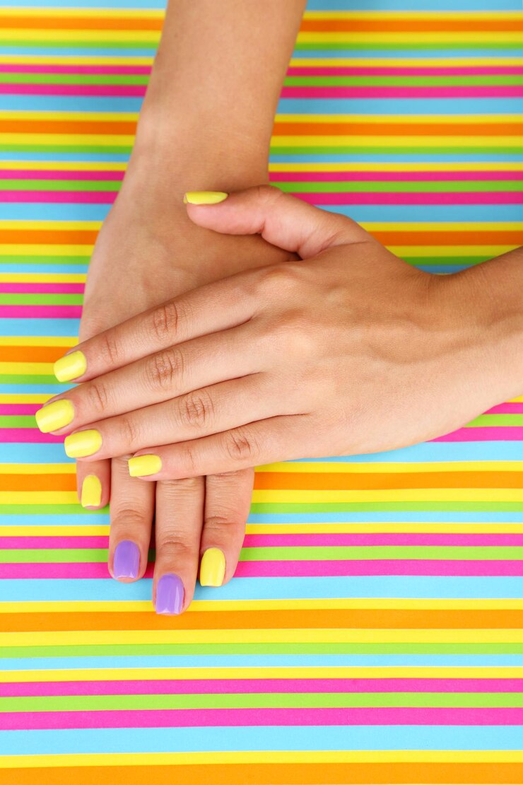 Foto mão feminina com unhas coloridas e elegantes em fundo brilhante