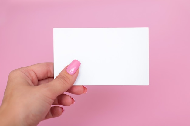 Foto mão feminina com unhas de manicure rosa segurando um cartão de visita