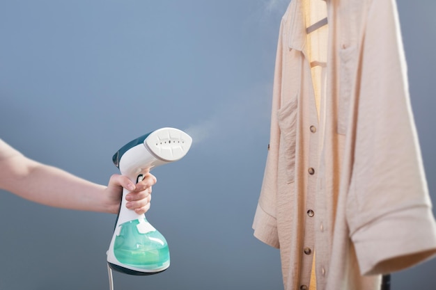 Mão feminina com vapor e camisa em fundo azul