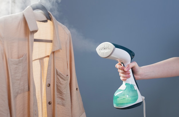 Mão feminina com vapor e camisa em fundo azul