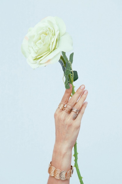 Foto mão feminina em jóias de moda segurando rosas brancas amante minimalista conceito estético