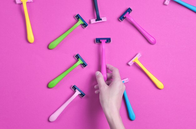Mão feminina escolhendo navalha verde entre uma variedade de depiladoras coloridas