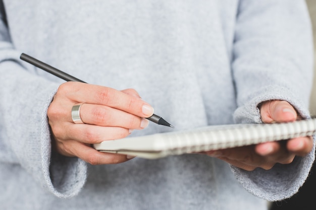 Mão feminina escrevendo no caderno de papel pesa