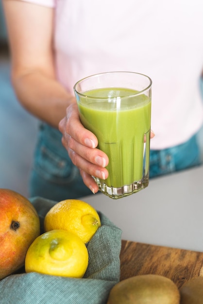 Foto mão feminina irreconhecível segurando um copo de smoothie verde fresco e saudável