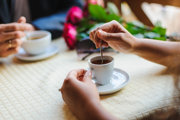 Mão feminina jovem mexa a xícara de café no café