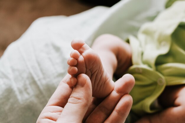 Mão feminina massageando os pés do bebê recém-nascido