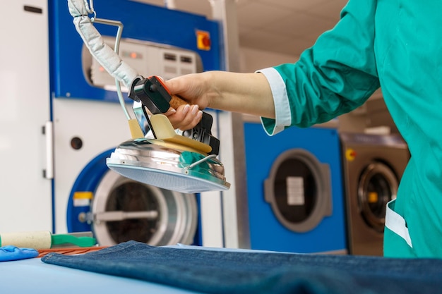 Mão feminina passando jeans azul em um serviço de limpeza a seco