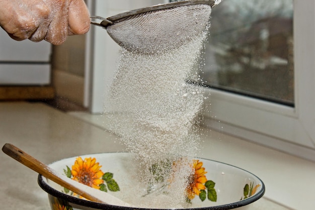 Foto mão feminina peneirando farinha através de peneira manual de farinha em uma tigela cópia de close-up espaço de cozimento de massa utensílio de cozinha de metal