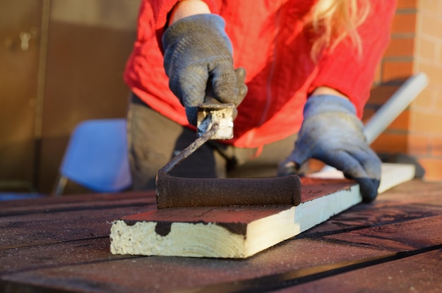 Mão feminina pintando madeira com rolo de pintura