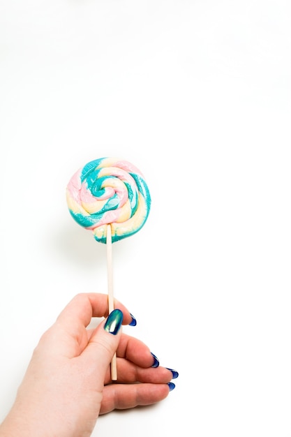 Mão feminina segurando balas de caramelo coloridas em um fundo branco