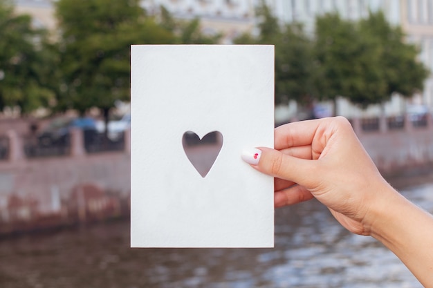Mão feminina segurando cartão postal com espaço de cópia no fundo do rio