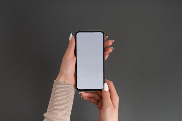 Mão feminina segurando e tocando no smartphone móvel com tela branca Isolado em cinza Modelo de foto para qualquer imagem no visor do celular Layout com fundo de monitor de telefone facilmente removível