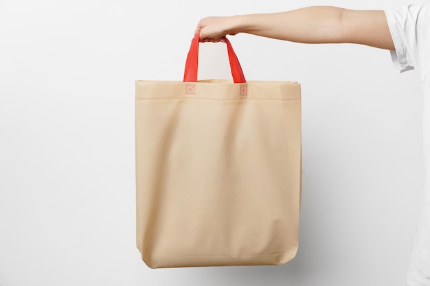 Mão feminina segurando eco ou sacola de compras reutilizável contra fundo branco