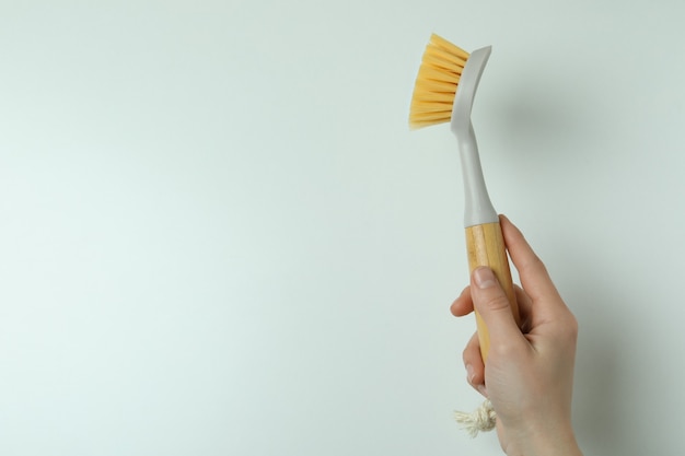 Mão feminina segurando escova ecológica em fundo branco