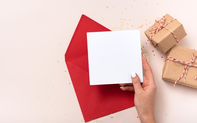 Mão feminina segurando maquete de papel quadrado em branco vermelho Natal