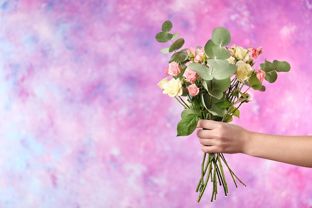 Mão feminina segurando o buquê de rosas na cor de fundo