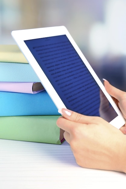 Mão feminina segurando o tablet pc perto de livros closeup conceito de educação moderna