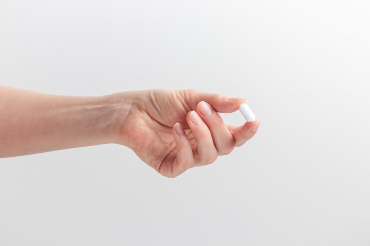 Mão feminina segurando pílula branca com dedos em fundo branco Conceito de cuidados de saúde suplementos dietéticos tratamento de depressão e doenças Banner de foto de alta qualidade