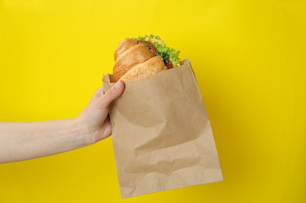 Foto mão feminina segurando sanduíche de croissant em amarelo