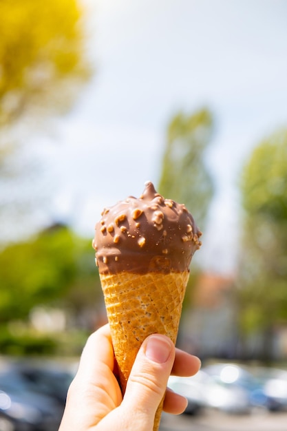 Mão feminina segurando um delicioso sorvete de chocolate com baunilha americano Saboroso sorvete caseiro Gelato no cone de waffle Sem glúten vegan sem laticínios