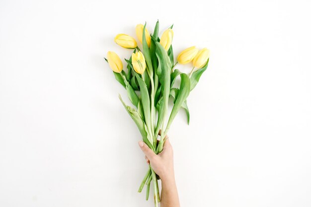 Mão feminina segurando um lindo buquê de flores de tulipa amarela em branco