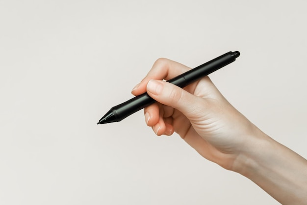 Foto mão feminina segurando uma caneta preta para tablet gráfico em um fundo cinza