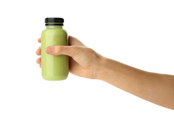 Foto mão feminina segurando uma garrafa de suco de abacate em branco