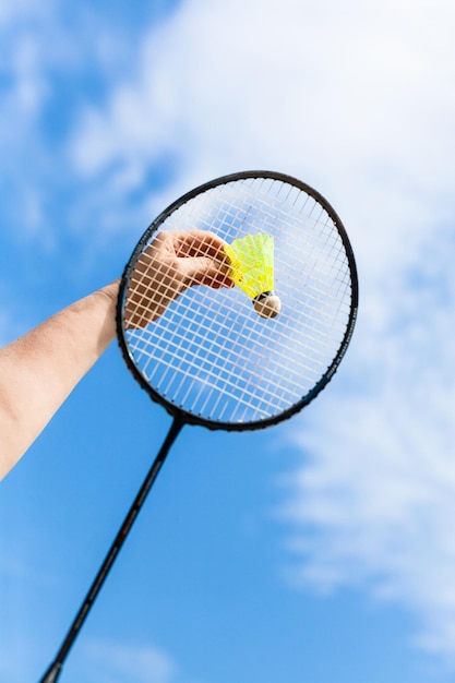 Mão golpeia peteca por raquete de badminton