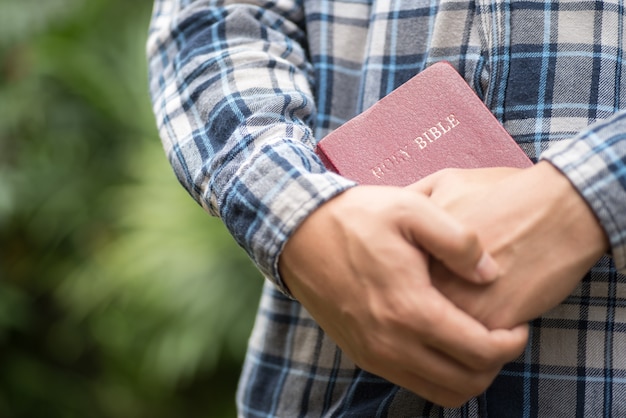 Mão humana colocada sobre a Bíblia, ore a Deus.