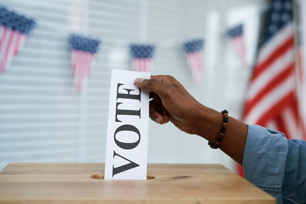 Mão humana colocando o cartão de voto na urna