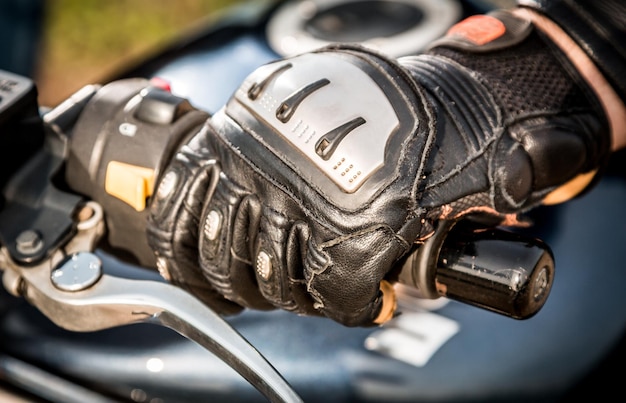 Mão humana em luvas de motociclismo detém um controle de aceleração de motocicleta. Proteção das mãos contra quedas e acidentes.