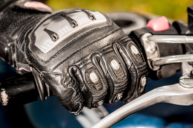 Mão humana em luvas de motociclismo detém um controle de aceleração de motocicleta. Proteção das mãos contra quedas e acidentes.