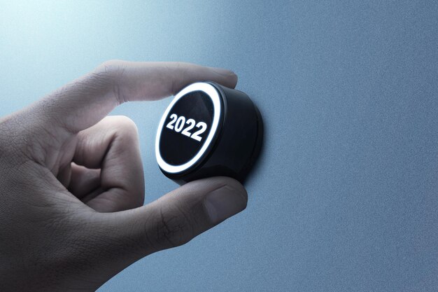Mão humana girando o botão 2022. Feliz ano novo 2022