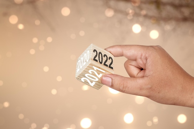 Foto mão humana mostrando o lado de 2022 no cubo de madeira. feliz ano novo 2022